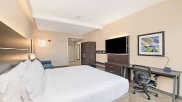 Una habitación de hotel con una cama grande, un escritorio con silla, un televisor de pantalla plana y un cuadro abstracto enmarcado en la pared.