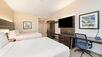A hotel room with a large bed, a desk with a chair, a TV, and artwork on the walls.