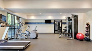 Un gimnasio con cintas de correr, elípticas, máquinas de pesas y diferentes pelotas de ejercicio.