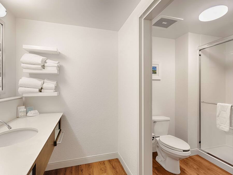 Une salle de bain moderne avec un lavabo, des toilettes et une douche, le tout de couleur blanche.