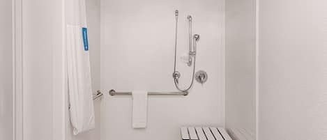 A shower area with a grab bar, a bench, and a towel rack.