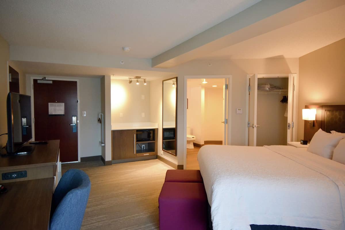 A hotel room with a bed, a desk, a chair, a closet, and a bathroom.