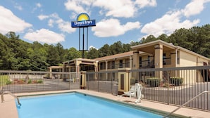 Um Days Inn by Wyndham com piscina, área de estar externa e um pátio cercado.