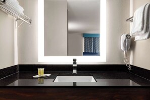 A modern bathroom with a large mirror, a sink, and a towel rack.