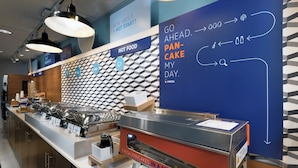 A breakfast buffet area with labeled food stations and a wall with directional signage.