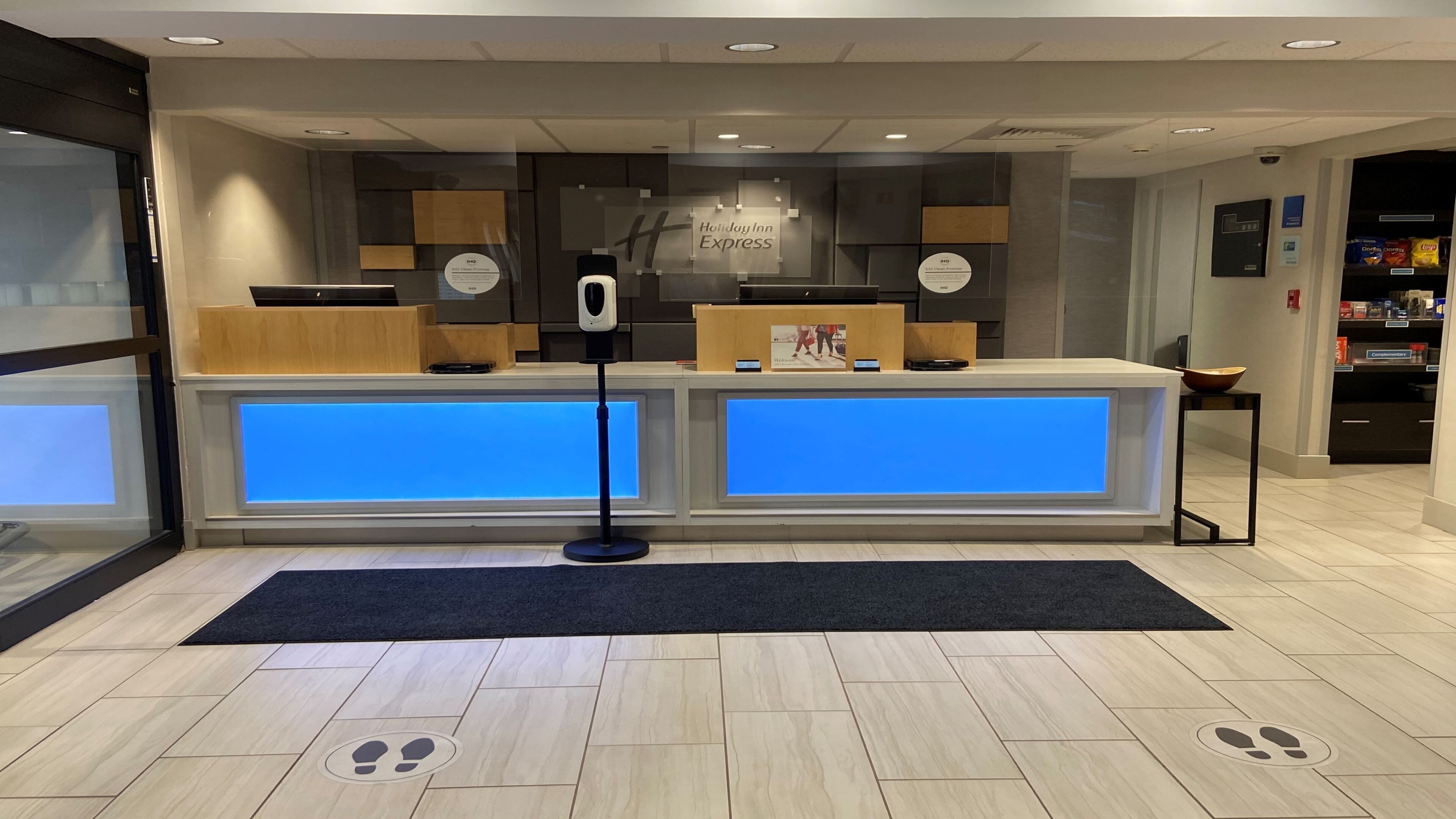 A reception desk with a blue illuminated panel, a security camera, and a sign for Holiday Inn Express.
