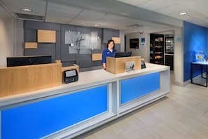 A hotel reception desk with a digital kiosk, a computer, and a sign for Holiday Inn Express.