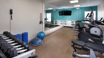 A gym with exercise equipment, a mirror, and a wall-mounted emergency phone.