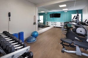 A gym with exercise equipment, a mirror, and a wall-mounted emergency phone.