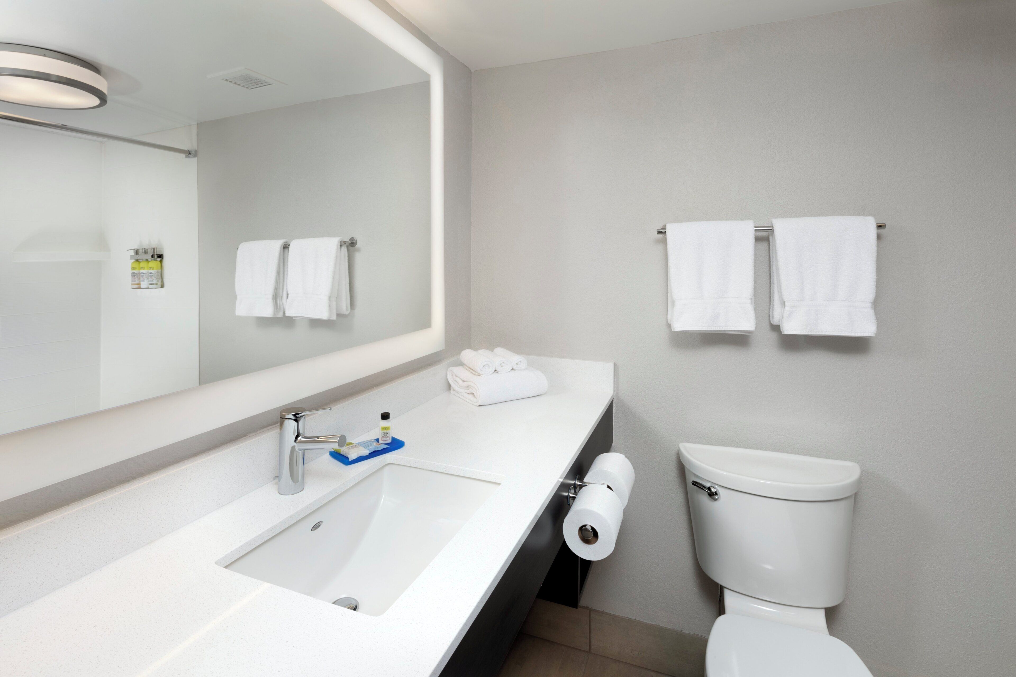 A modern bathroom with a white sink, mirror, and toilet.