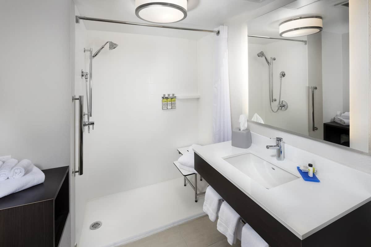 A modern bathroom with a walk-in shower, a large mirror, and a dual sink vanity.