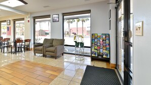 A lobby with a seating area, a ceiling fan, a coffee machine, and a window with a view of palm trees. - OYO Hotel Lake Park/Valdosta I-75, Exit 5 (Lake Park)