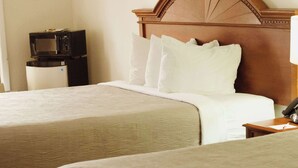 A hotel room with two beds, a wooden headboard, a bedside table with a lamp, and a microwave on a small table. - Quality Inn near Chattanooga South (Ringgold)