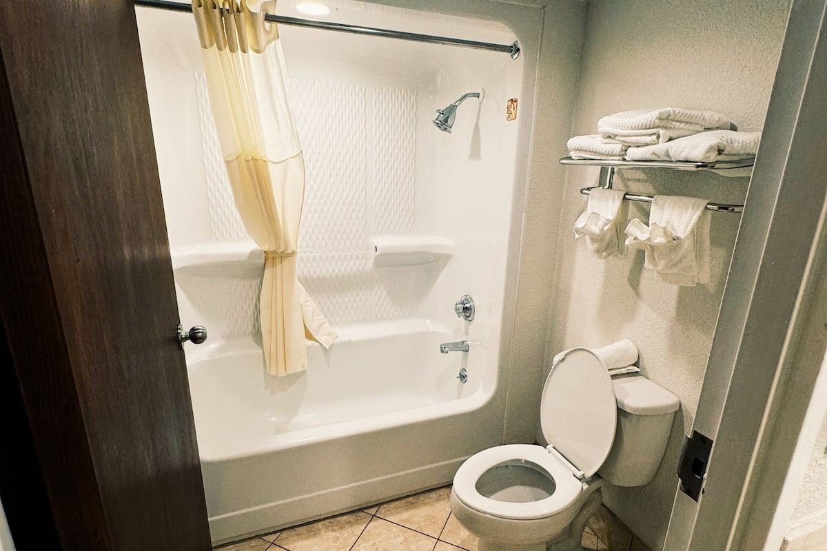 A bathroom with a bathtub, toilet, and a towel rack.