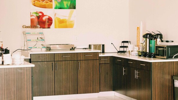A modern kitchen with wooden cabinets, a coffee machine, and a microwave. - Quality Inn near Chattanooga South (Ringgold)