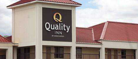 A multi-story hotel with a prominent sign for Quality Inn by Choice Hotels.