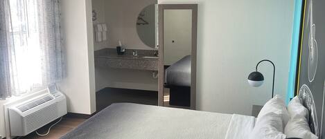 A bedroom with a large bed, bedside lamp, and a view of the bathroom.