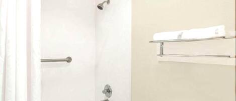 A bathroom with a bathtub, a shower, and a toilet. There are towel racks above the toilet.