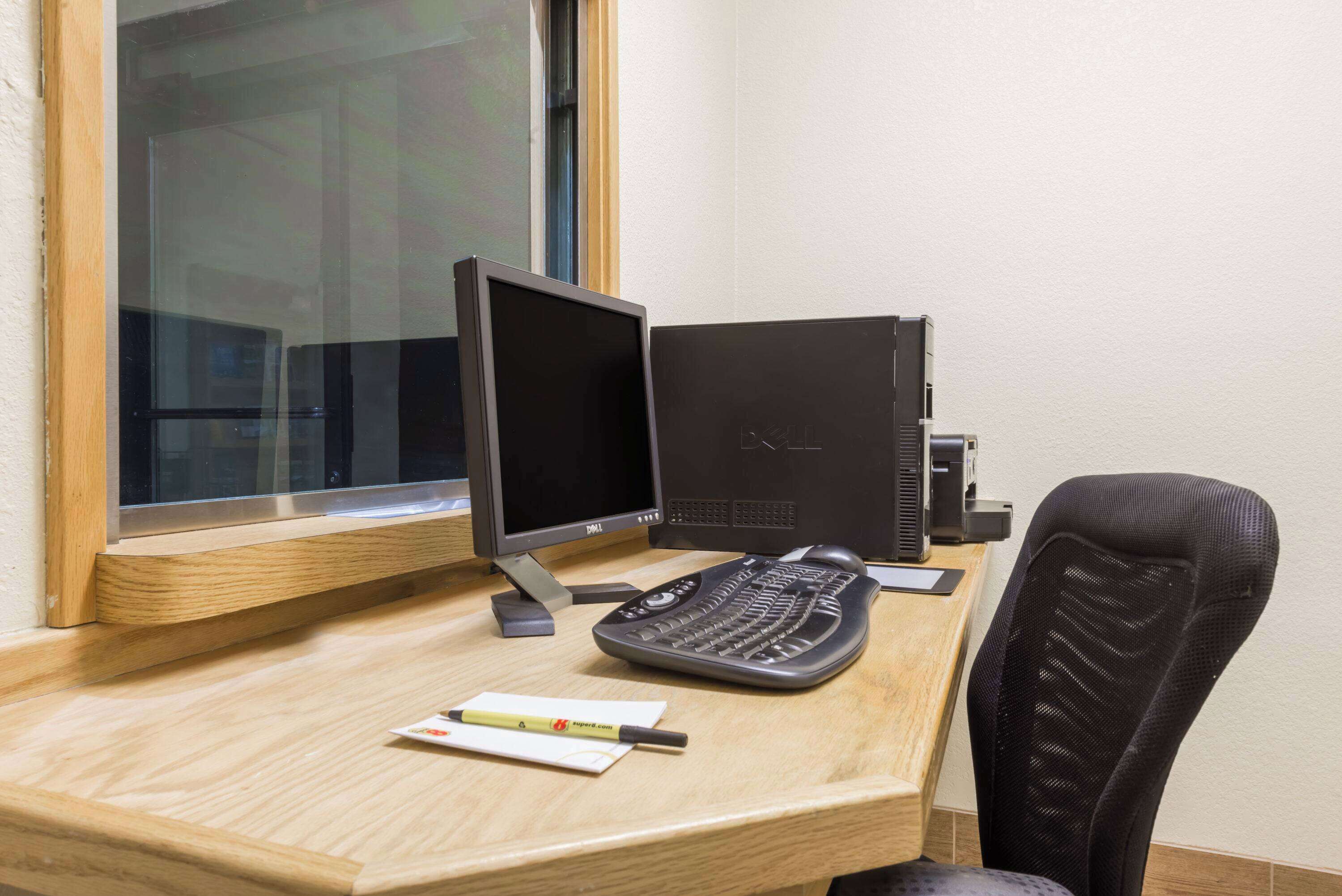 A wooden desk with a computer setup including a monitor, keyboard, and mouse.