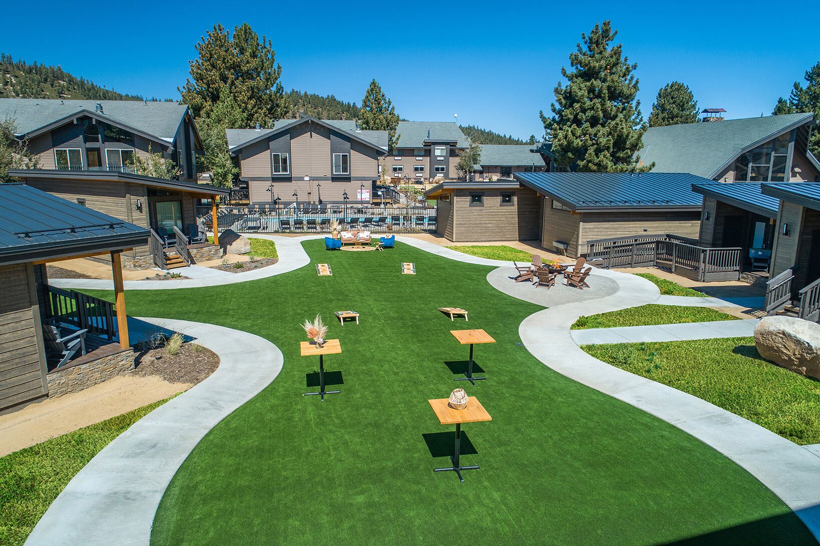 A modern outdoor patio area with multiple seating arrangements and a central fire pit.