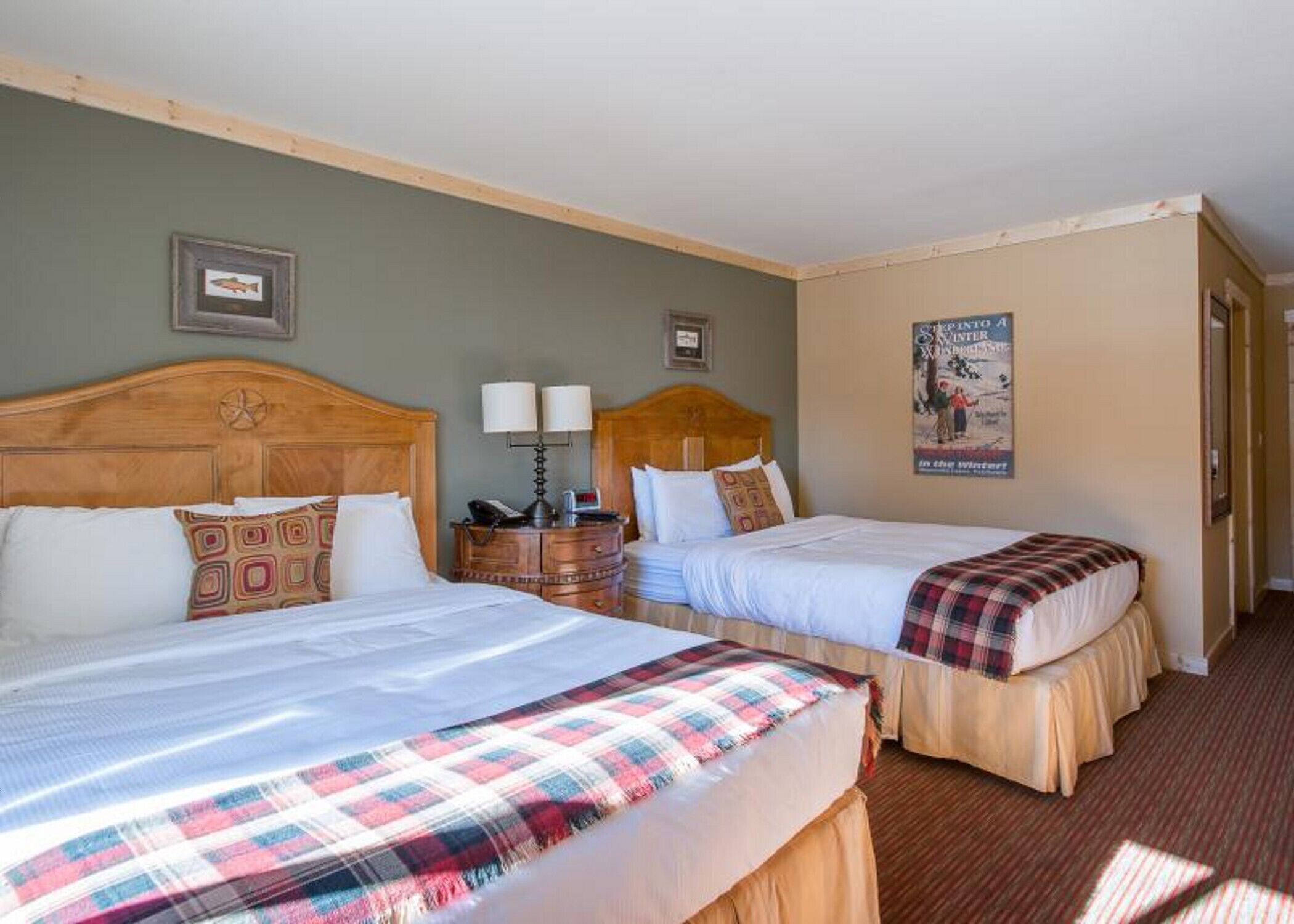 A hotel room with two beds, a wooden headboard, a nightstand, and a poster on the wall.