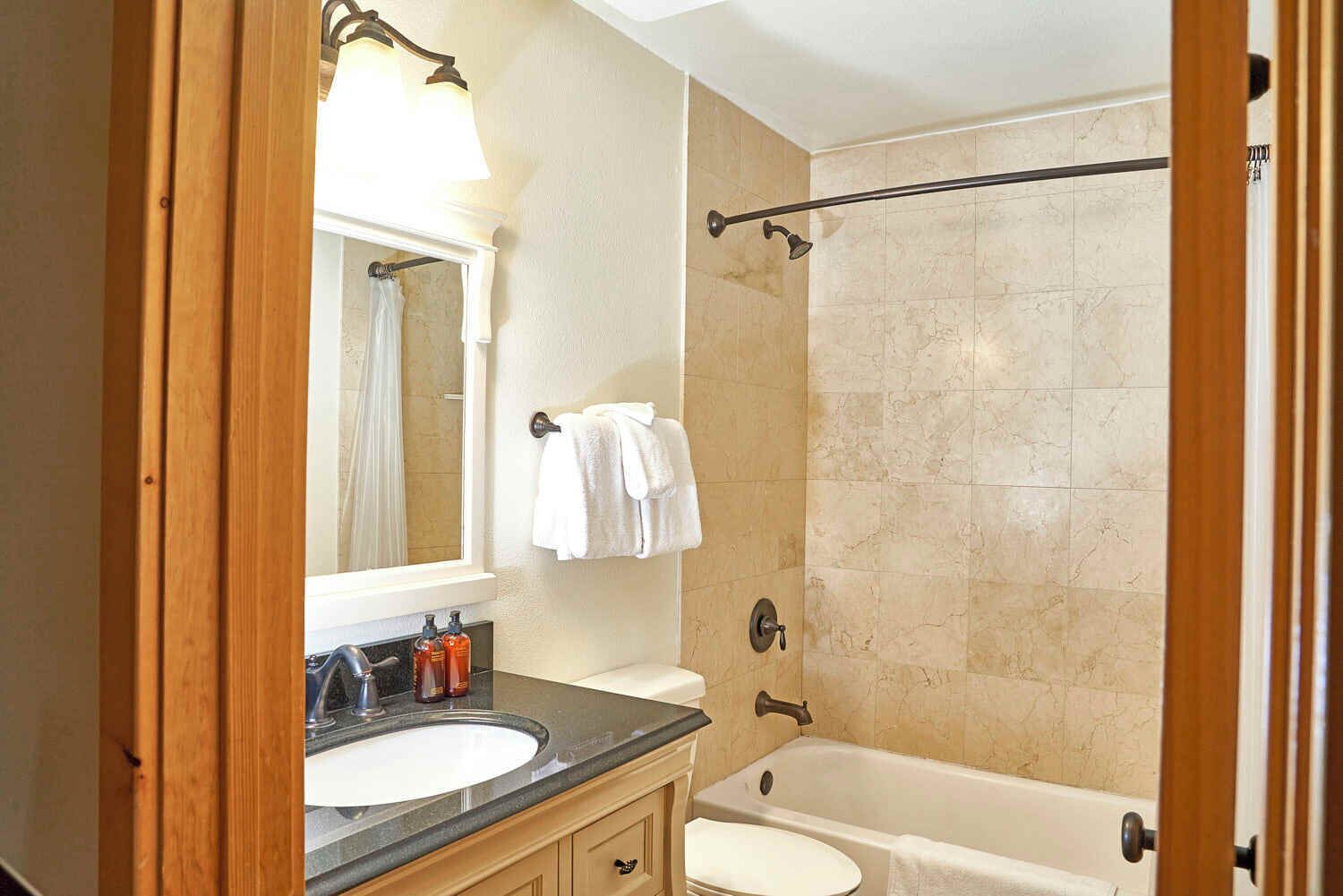 A bathroom with a sink, mirror, and bathtub.