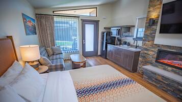 Une chambre d’hôtel comprenant un lit, un canapé, une petite table, un coin cuisine et une cheminée.