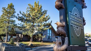 A sign for Outbound Mammoth with a bear sculpture and a mountain backdrop. - Outbound Mammoth  (Mammoth Lakes)