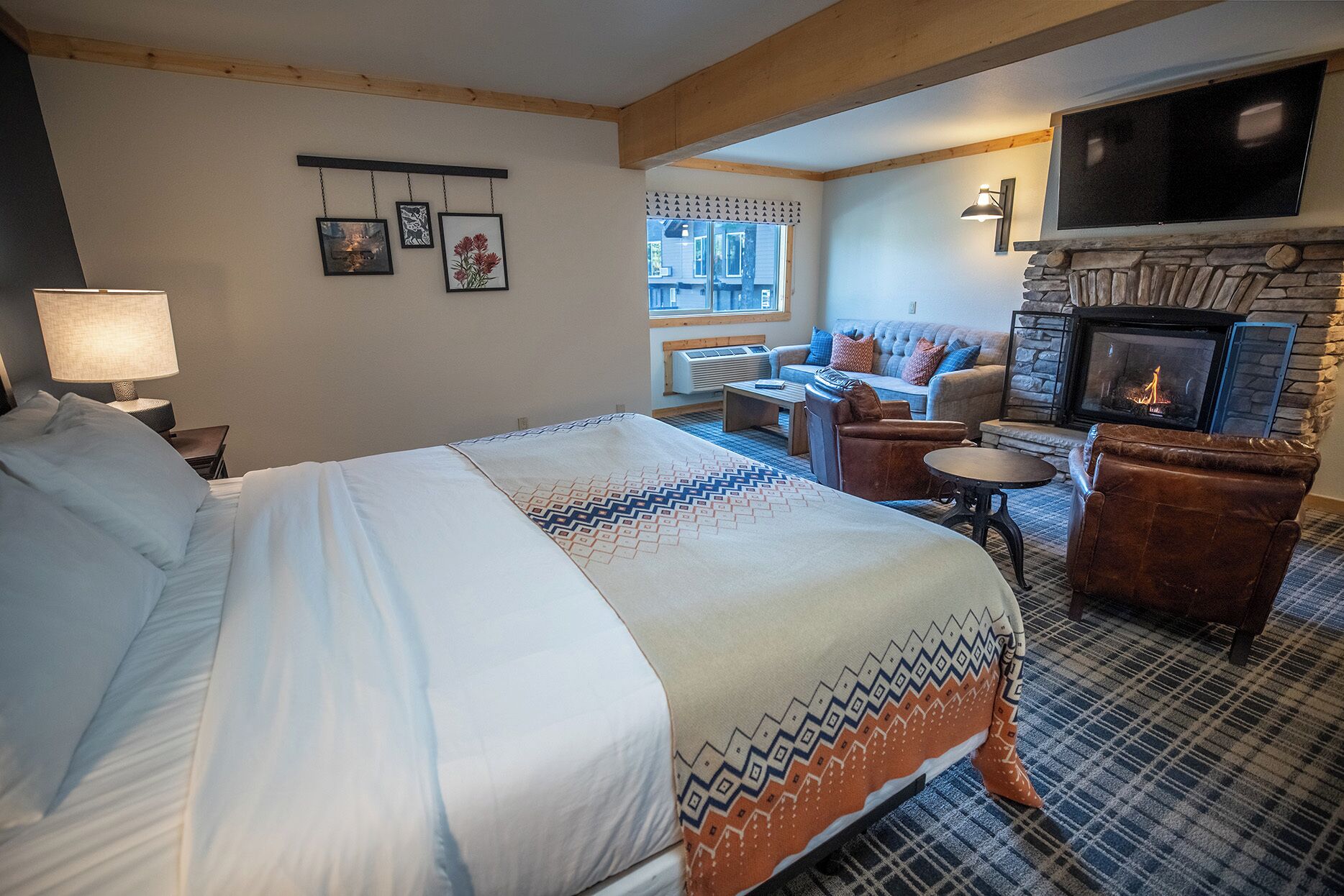 A hotel room with a large bed, a fireplace, a sofa, and a television.
