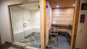 A sauna with a glass door, wooden walls, and a tiled floor.