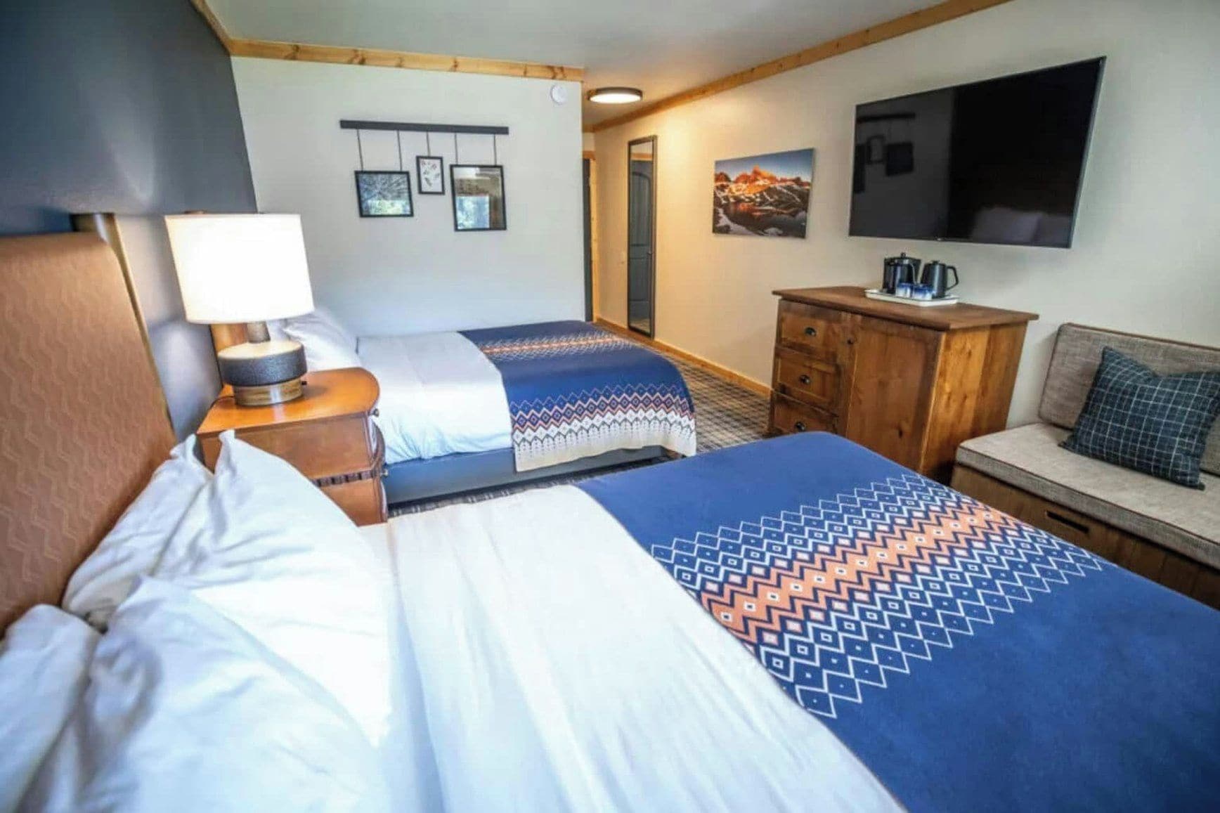Ett hotellrum med två sängar, en TV, en kaffebryggare och en byrå i trä.