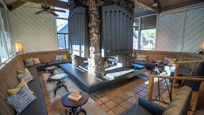 A spacious living area with a stone fireplace, comfortable seating, and a ceiling fan. - Outbound Mammoth  (Mammoth Lakes)