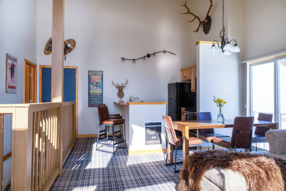 A cozy kitchen with a central island, wooden chairs, a dining table, and a refrigerator.