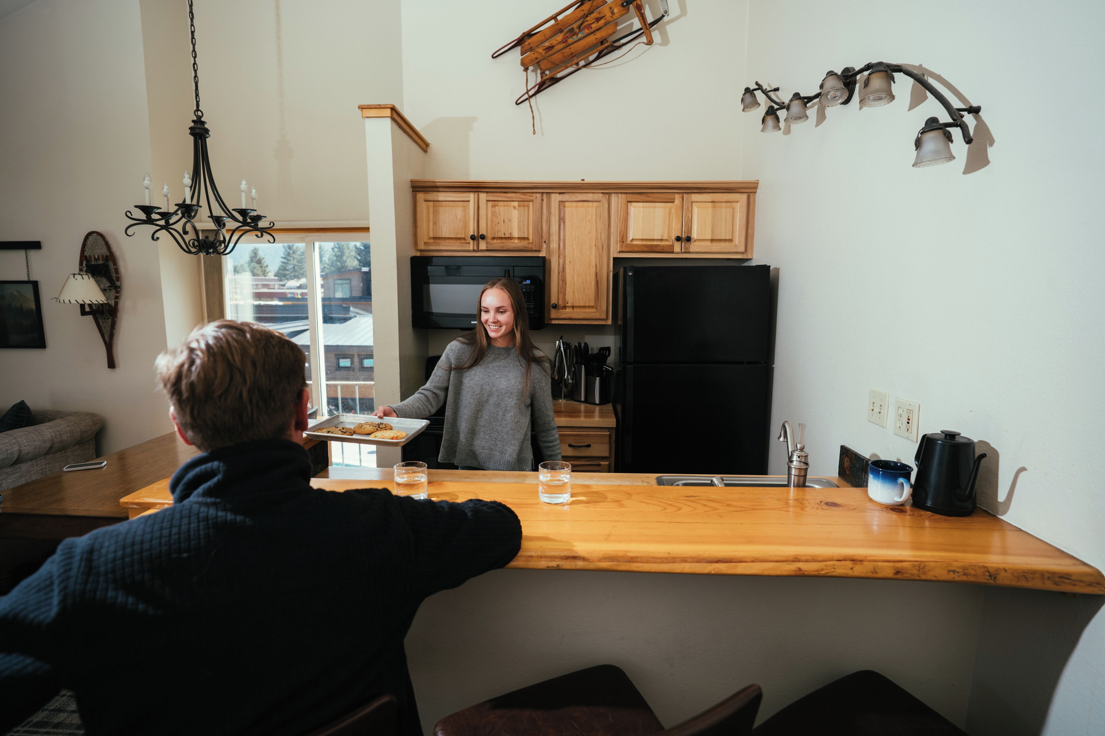 A kitchen with wooden cabinets, a black refrigerator, and a wooden countertop.