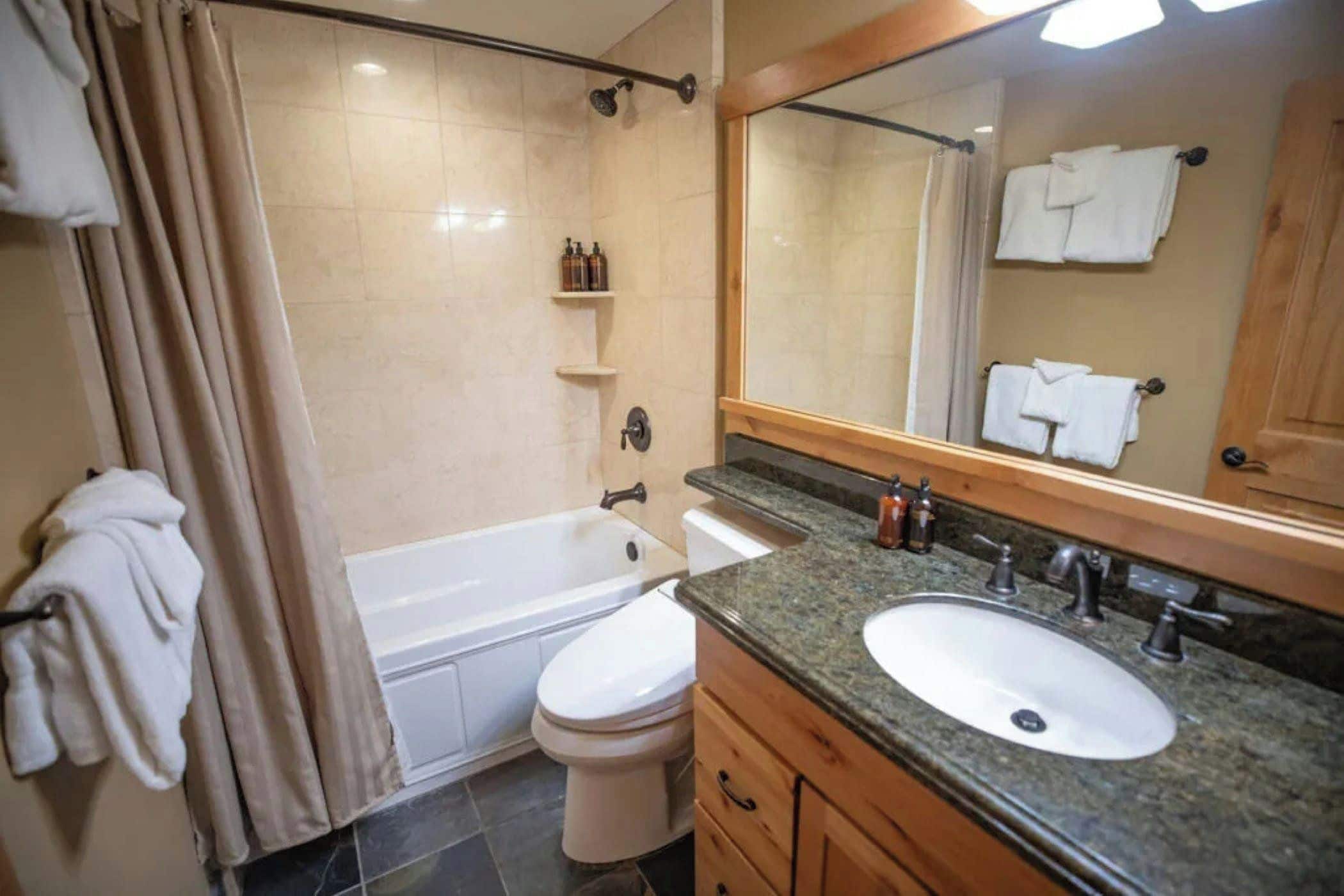 Ein Badezimmer mit Badewanne, Toilette, Waschbecken und Spiegel.