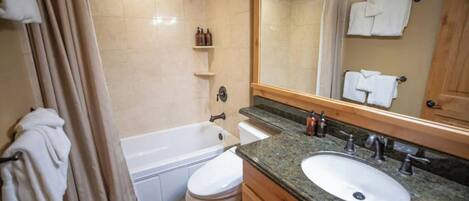 A bathroom with a bathtub, toilet, sink, and a mirror.