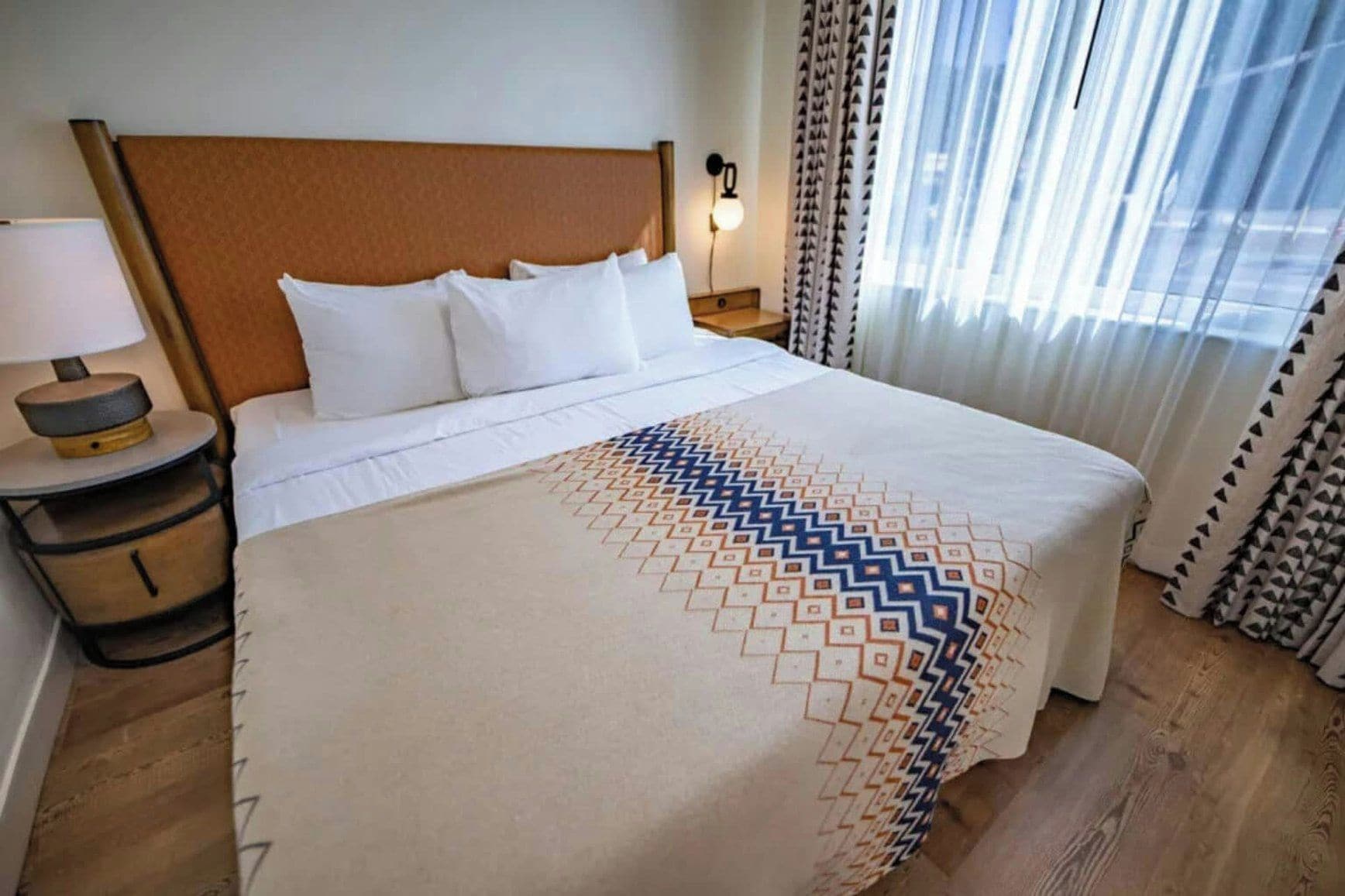 Une chambre d’hôtel avec un grand lit, une lampe de chevet et des rideaux.