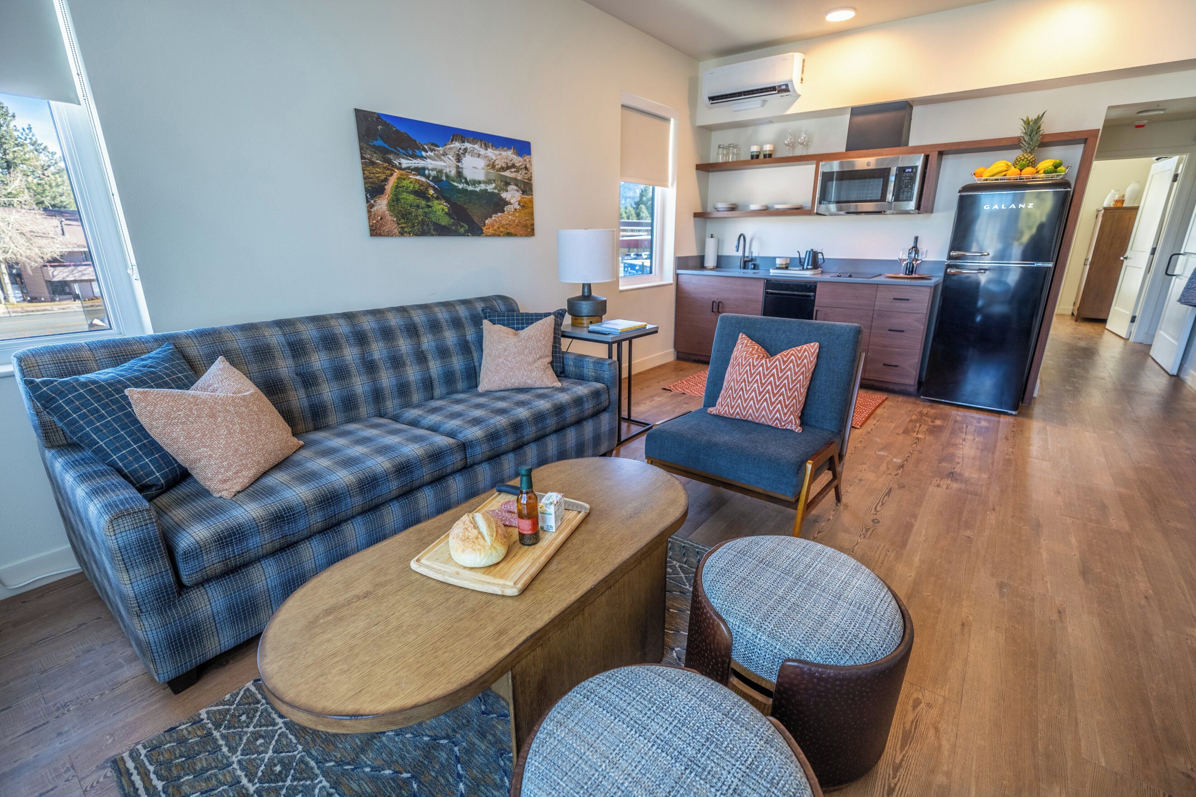 A modern living room with a sofa, a dining table, and a kitchen in the background.