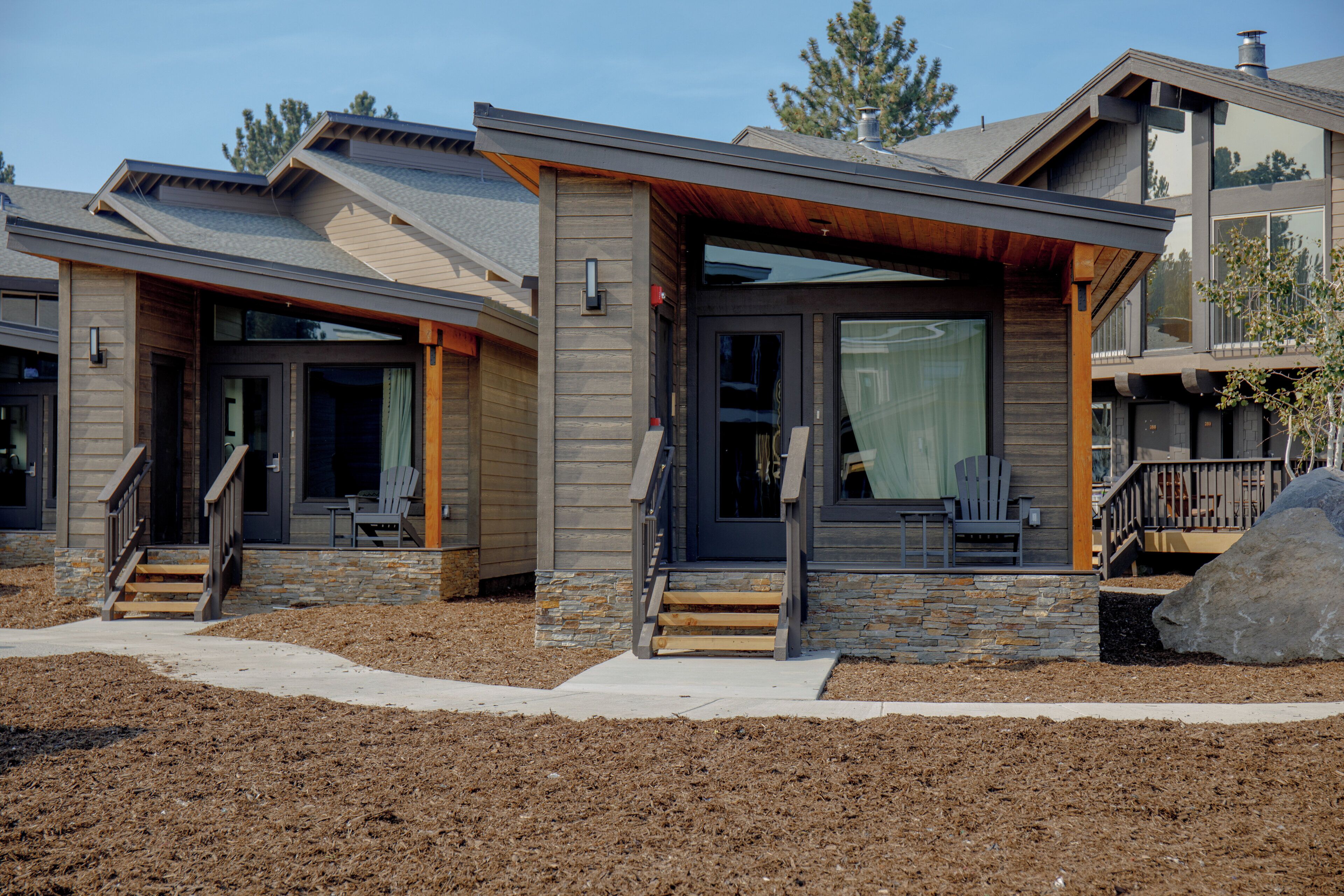 A modern two-story house with a stone foundation, wooden siding, and a covered front porch.