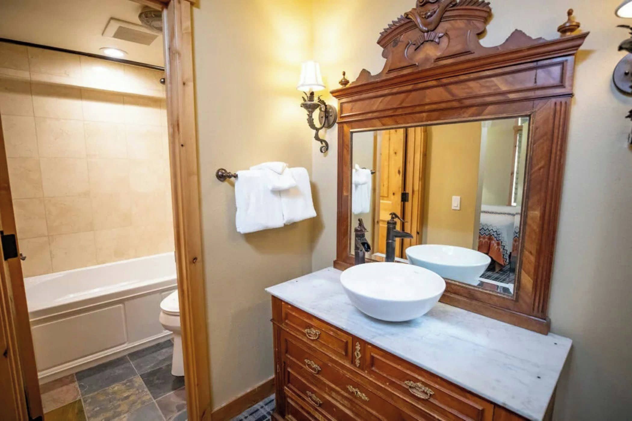 A bathroom with a bathtub, a sink with a large mirror, and a towel rack.