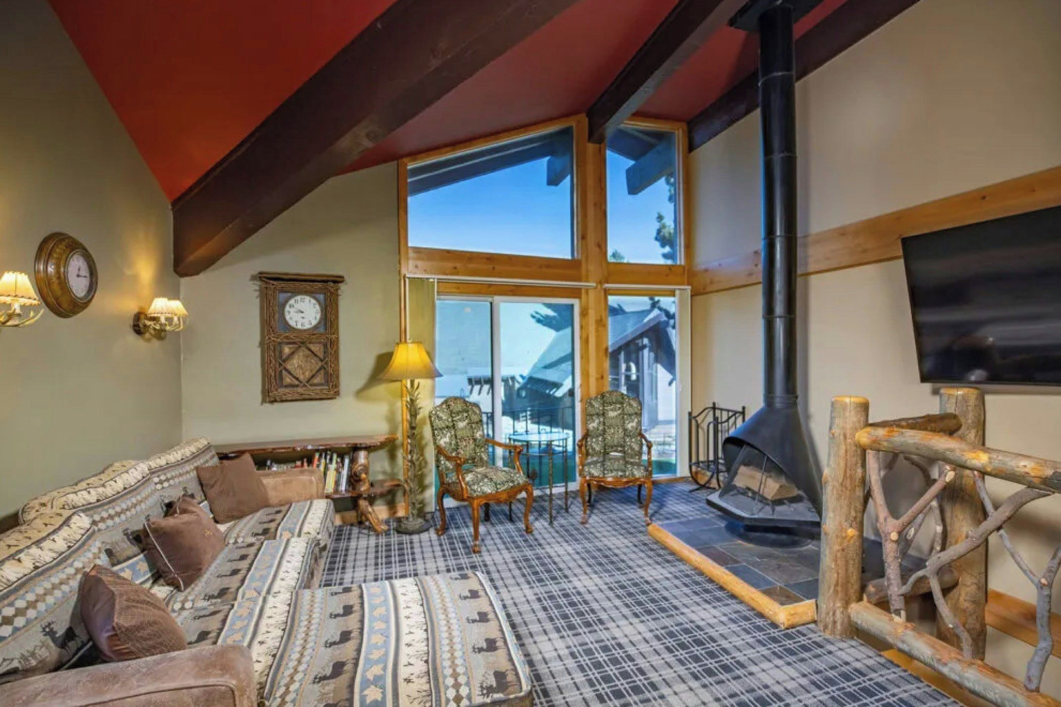 A cozy living room with a fireplace, large windows, and a view of the outdoors.