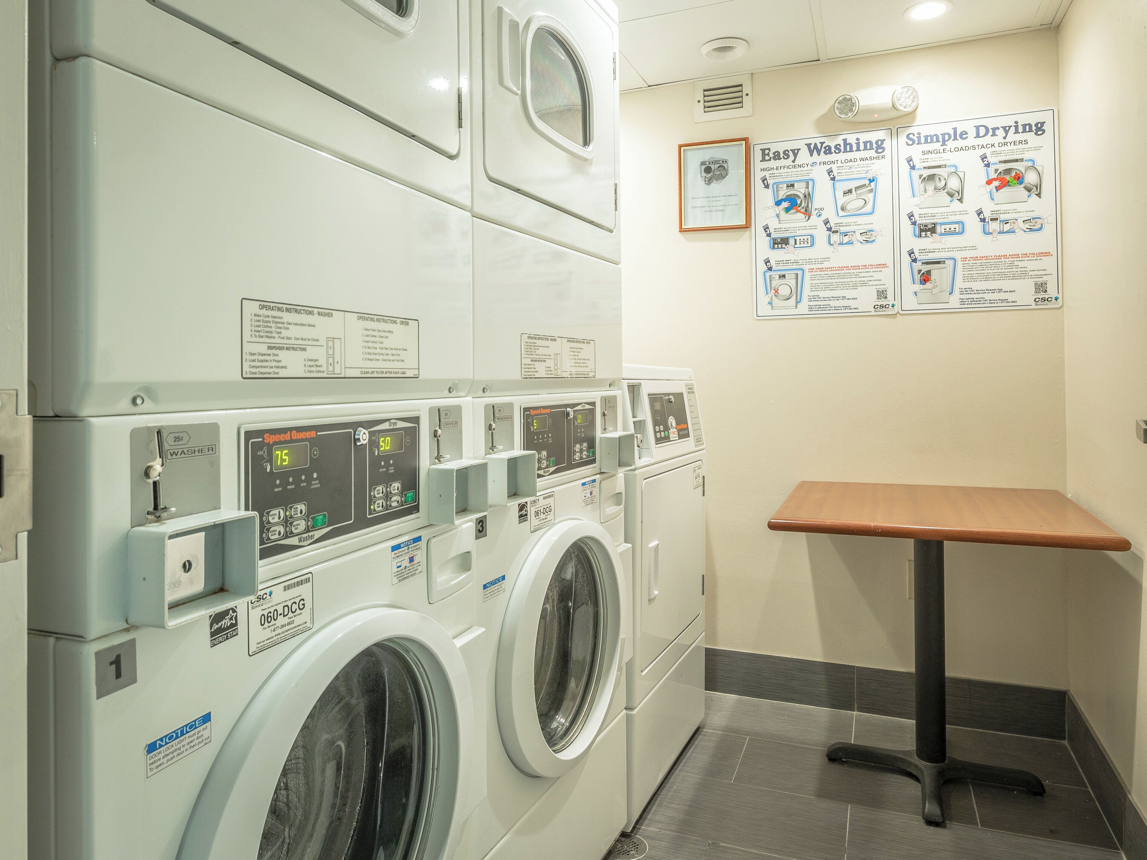 A laundry facility with multiple washing machines and dryers, operating instructions, and safety notices.