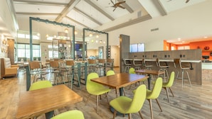 A spacious indoor area with multiple tables and chairs, a ceiling fan, and a kitchen area in the background. - Holiday Inn Hotel & Suites Peachtree City by IHG (Peachtree City)