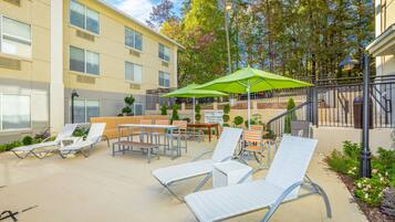 Een buitenzwembad, ligstoelen bij het zwembad