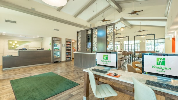 A Holiday Inn reception area with a wooden floor, green carpet, and a reception desk with computers. - Holiday Inn Hotel & Suites Peachtree City by IHG (Peachtree City)