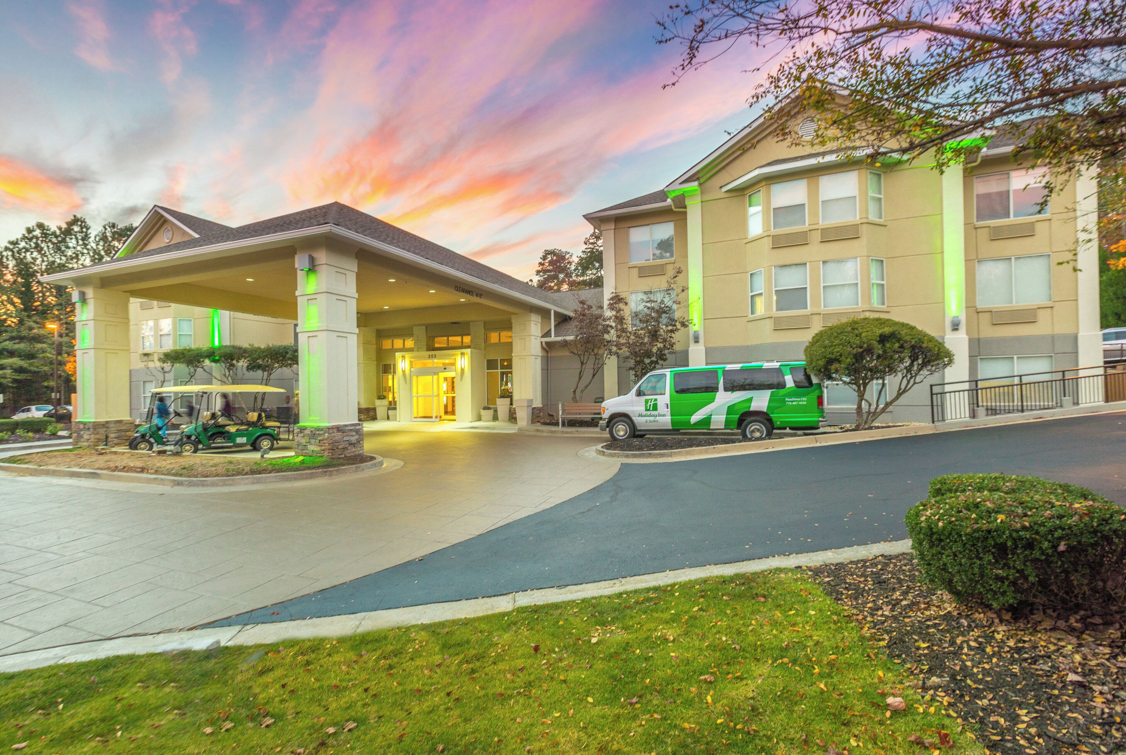 A hotel entrance with a covered driveway, a golf cart, and a green and white van parked outside.
