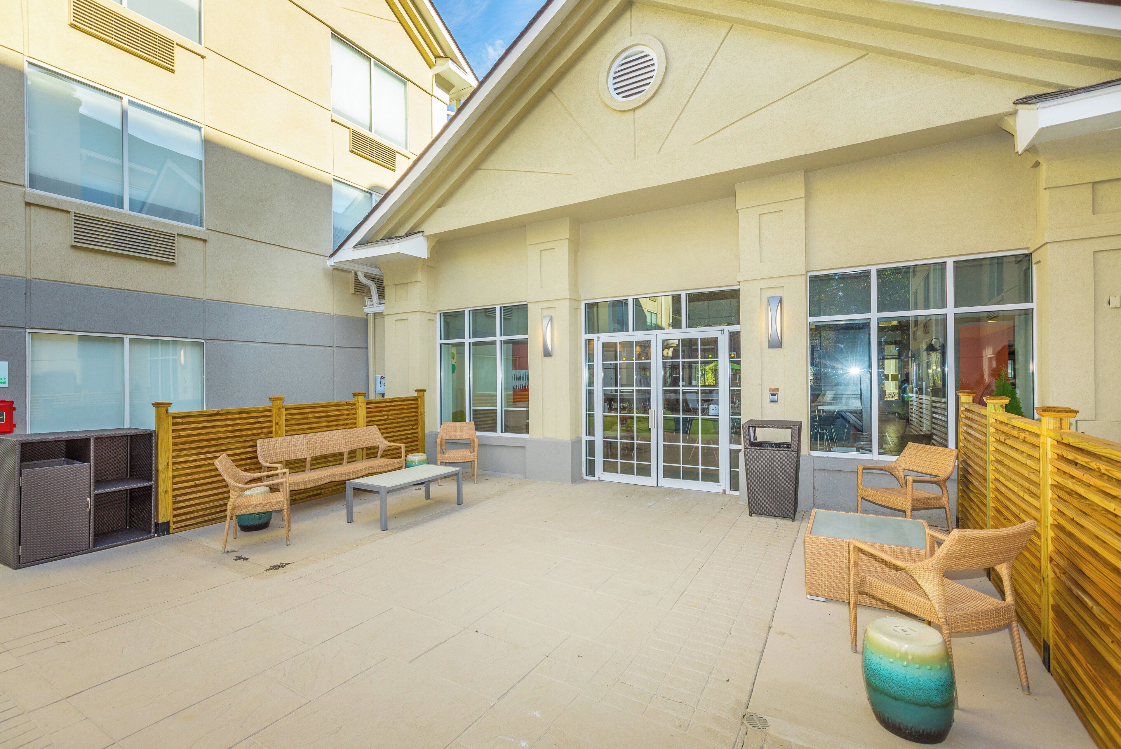 An outdoor seating area with a wooden bench, chairs, and a table.