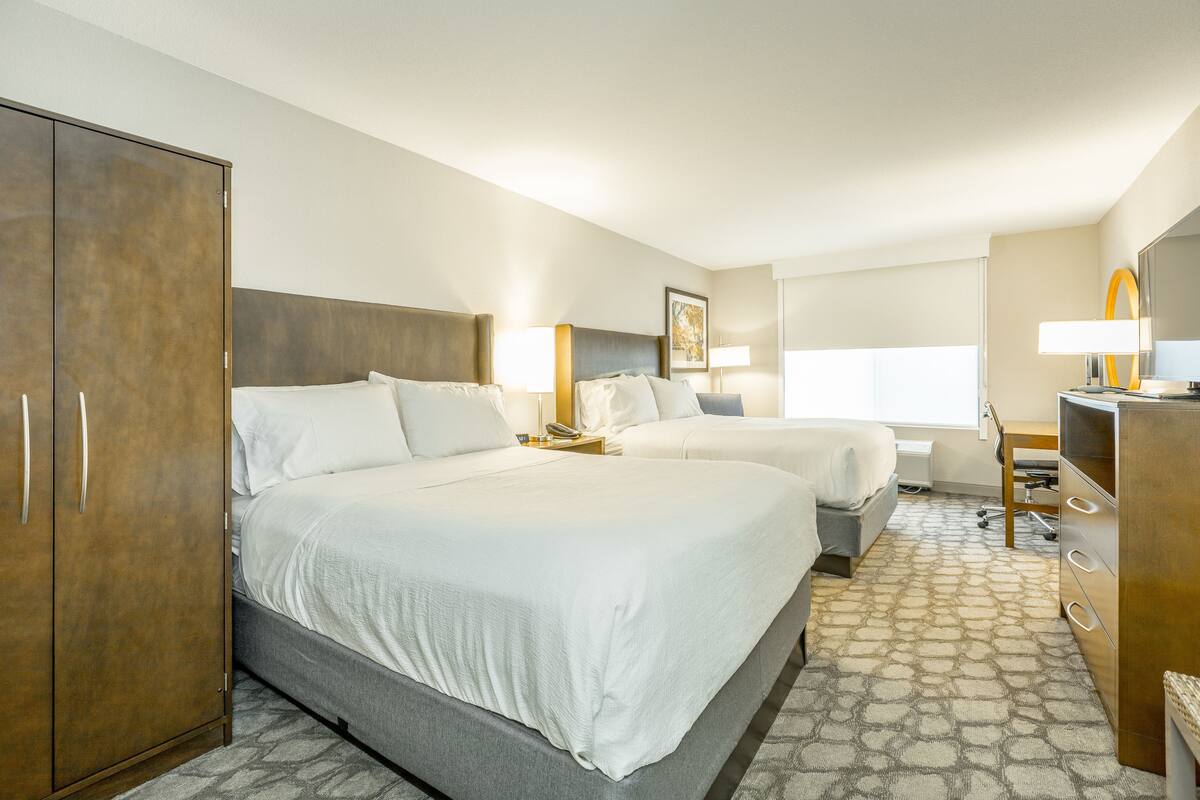 Une chambre d’hôtel avec deux lits, une armoire, un bureau et une chaise.