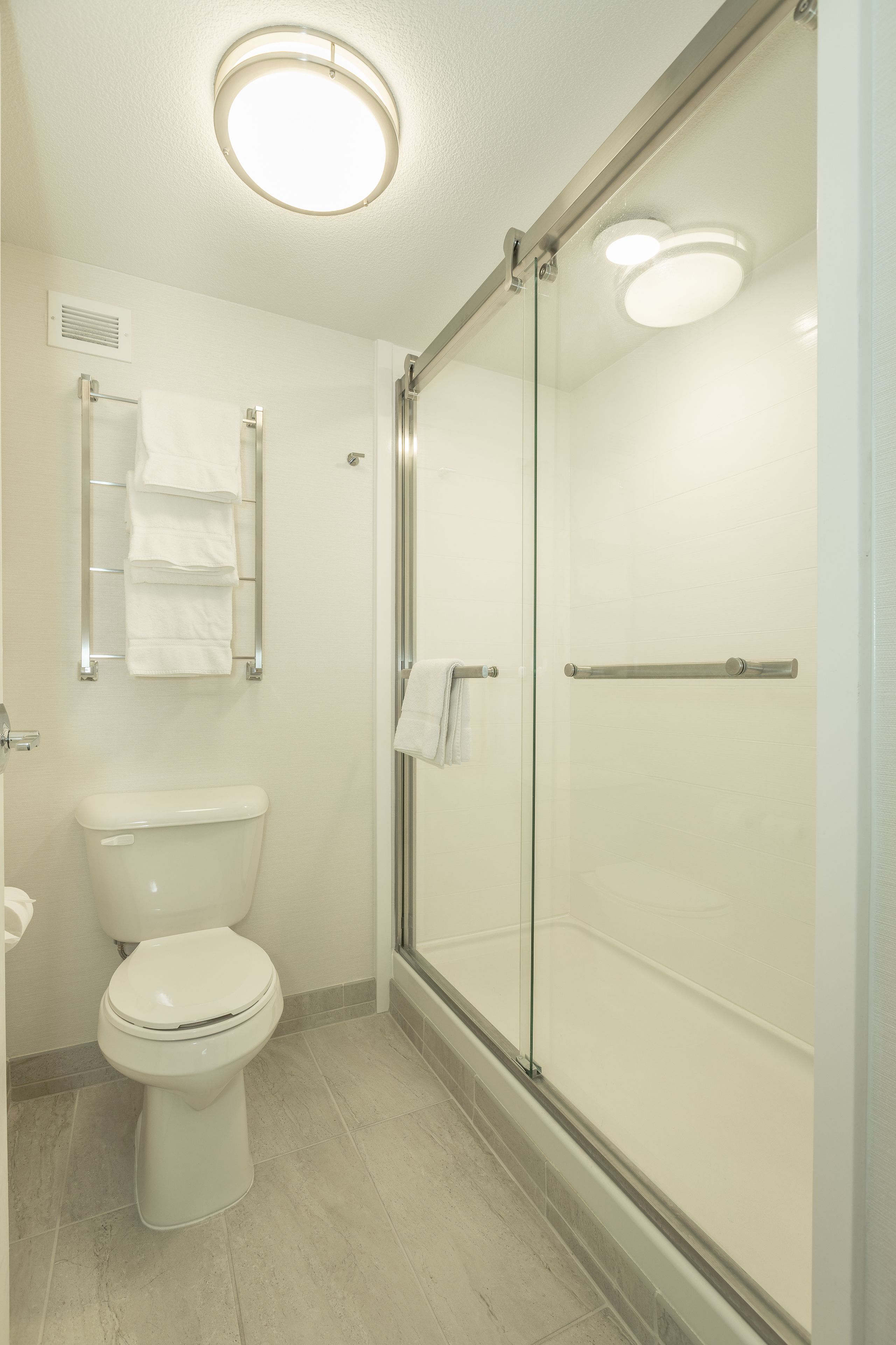 Une salle de bain moderne équipée de toilettes, d’une douche à parois de verre et d’un porte-serviettes.