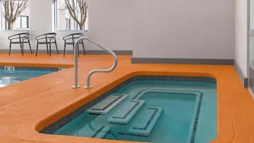 An indoor swimming pool with a clear water path, orange poolside, and chairs.